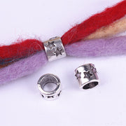 Silver beads with star patterns on a red and purple yarn background