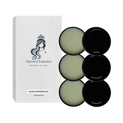 A set of three solid fragrance tins labeled as Holiday Scentiments Set by Aurora Essence, displayed in front of a white box with the brand's logo.